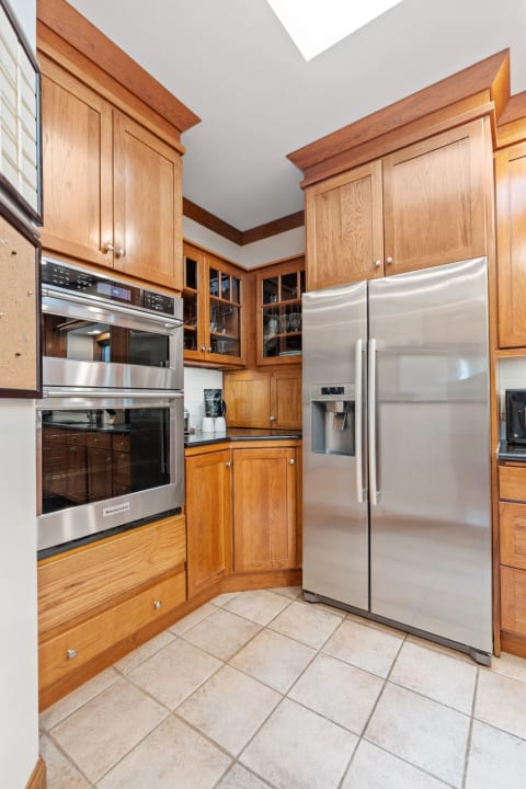 A kitchen corner with wood cabinetry, stainless steel appliances, and a skylight.