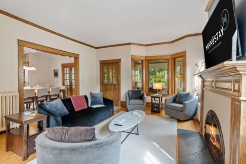 Cozy living room with black sofa, grey armchairs, marble coffee table, and fireplace.