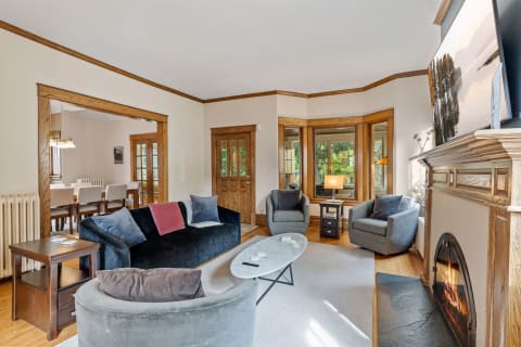 Cozy living room with navy blue sofa, gray armchairs, and a fireplace, creating an inviting atmosphere.