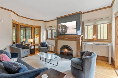 A cozy living room featuring plush gray furniture, a fireplace, and a TV above the mantel.