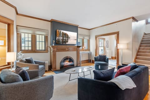 A cozy living room with plush seating, a fireplace, and a mounted TV, featuring warm wood accents.