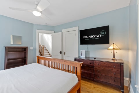 Peaceful bedroom featuring a double bed, dresser, ceiling fan, and a mounted TV.