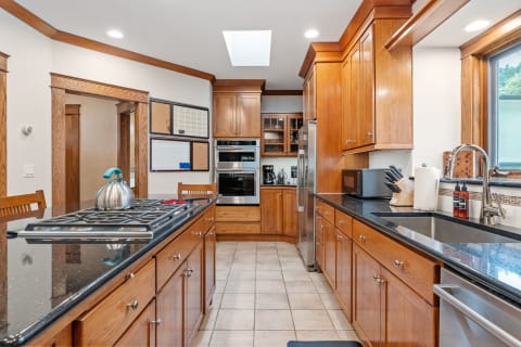 Modern kitchen with oak cabinetry, granite counters, and stainless steel appliances.