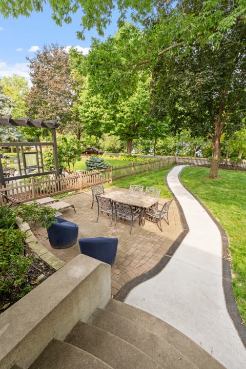 A beautiful garden patio with a dining table, surrounded by lush greenery and a winding path.