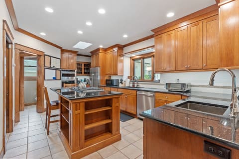 Gourmet kitchen featuring wood cabinetry, granite counters, and a spacious island.