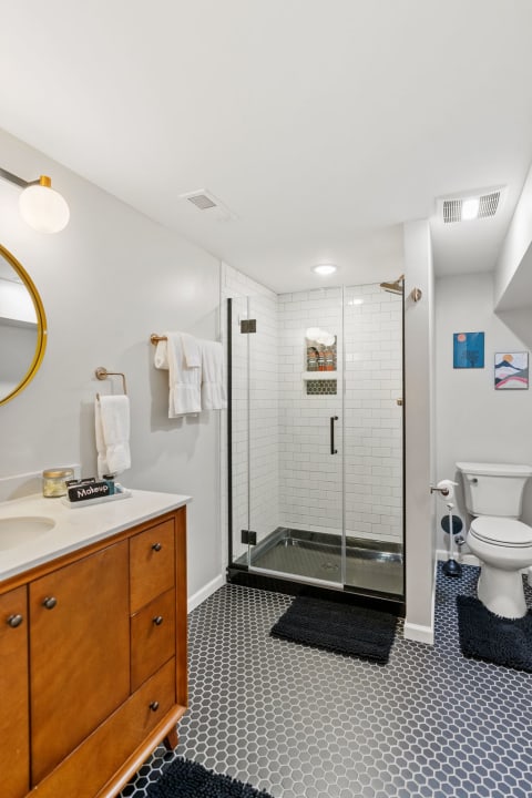 Modern bathroom showcasing a glass shower and wooden vanity with decorative elements.