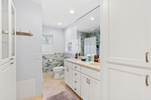 Bright and modern bathroom with two sinks, mosaic tiles, and a window.