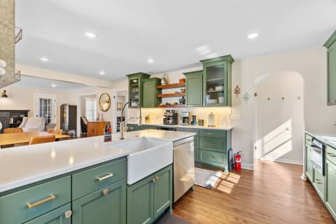 Modern kitchen with green cabinets and farmhouse sink, showcasing a welcoming design.