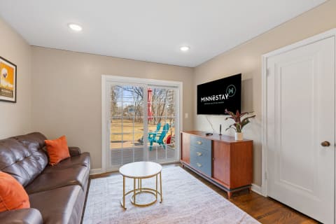 Cozy living room with leather couch, coffee table, and view of outdoor area with blue chairs.