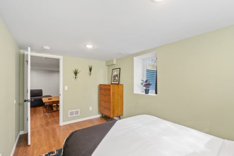Cozy bedroom featuring green walls, wooden flooring, and stylish furniture.