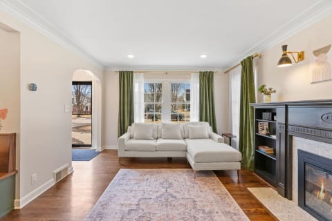 Living room featuring a sectional sofa, bookshelf, and fireplace with draped windows.