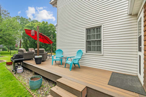 Outdoor deck area with turquoise chairs, a red umbrella, and a grill.