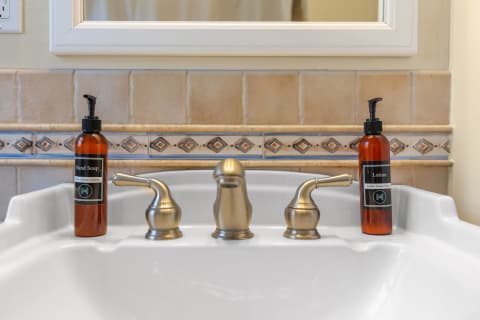 Close-up of a bathroom sink with hand soap and lotion bottles.