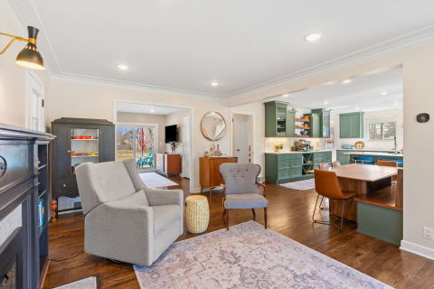 Interior view of a living area leading to a kitchen with green cabinets and a cozy seating arrangement.