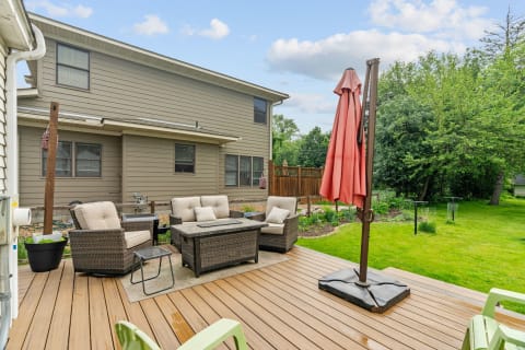 Cozy outdoor seating area with a wicker table and chairs on a deck, surrounded by greenery.
