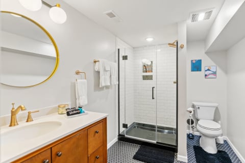 A contemporary bathroom with a glass shower, wooden vanity, and decorative wall art.