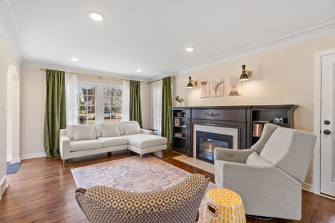 A bright living room with a sectional sofa, green curtains, and a black fireplace.