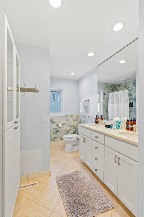 Modern bathroom with double sink, light blue walls, and decorative tile accents.