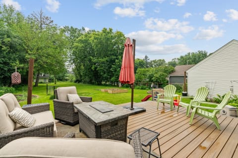 A cozy deck with wicker furniture and a view of a green backyard.