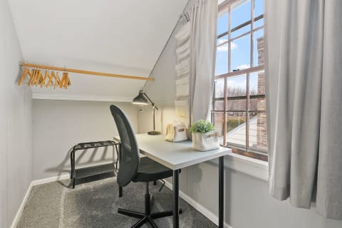 A small workspace featuring a desk, a chair, and natural light from a window.