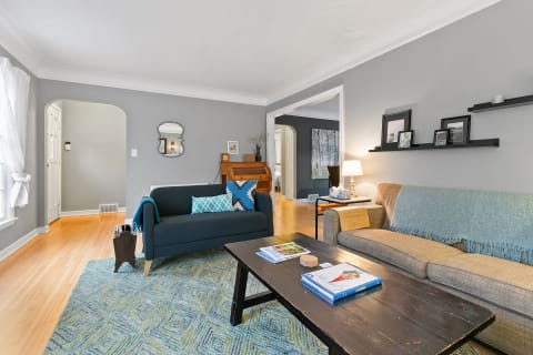 A beautifully decorated living room featuring a blue sofa, beige couch, wooden coffee table, and colorful area rug.
