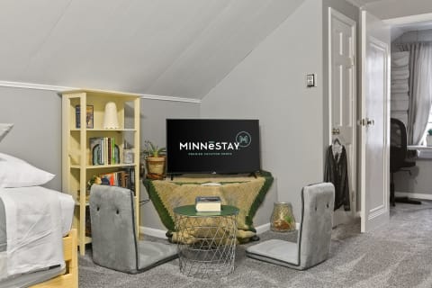 Interior view of a cozy room with a bed, TV, and bookshelf in soft colors.