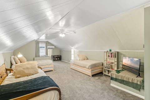 Spacious attic bedroom with two beds and a television.
