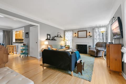 A cozy living room with gray walls and mixed furnishings, featuring a sofa, loveseat, and armchair.