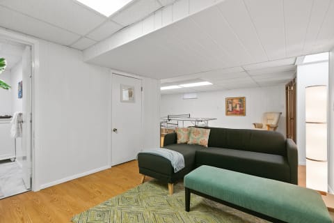 Modern living area with a sectional couch, decorative pillows, and a ping pong table in the background.
