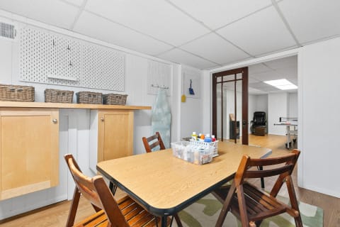 An organized multipurpose room with a wooden table and craft supplies.