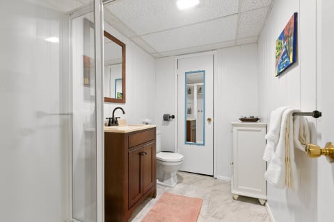 Interior view of a modern bathroom with a glass shower, wooden cabinetry, and decorative elements.