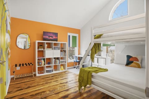 Cozy bunk room with orange walls, a white bunk bed, and modern decor.
