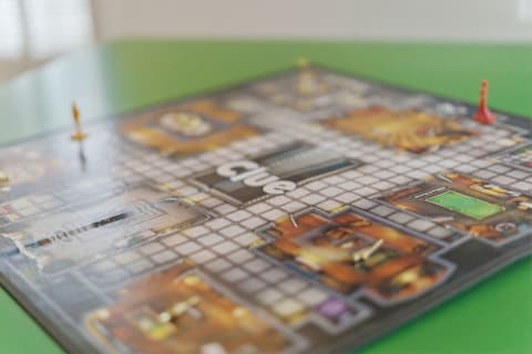 A colorful Clue board game with character tokens on a green tabletop.