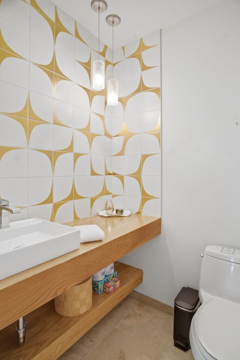 Chic bathroom with stylish gold and white geometric tiles and warm wood vanity.