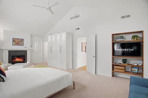 Cozy bedroom with a fireplace, entertainment center, and vaulted ceilings.
