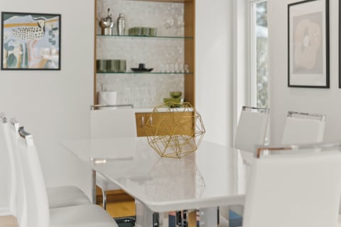Stylish dining area featuring a white table, white chairs, and a gold geometric sculpture.