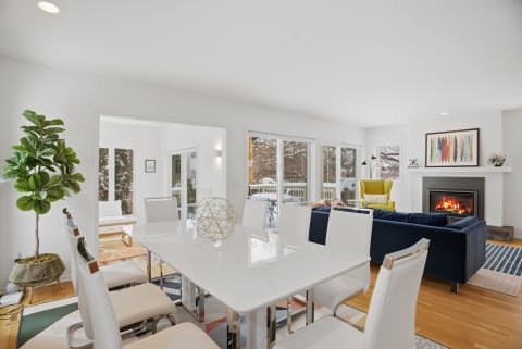 A stylish dining area and living room featuring a modern dining table, plush sofa, and a fireplace.