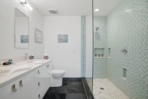Modern bathroom with mosaic tiles, a walk-in shower, and a double sink vanity.