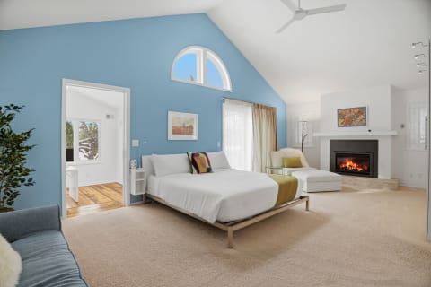 Spacious master suite with a cozy fireplace, vaulted ceilings, and blue accent wall.
