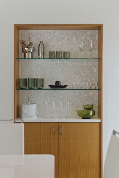 A stylish bar area with glass and cocktail essentials on display in an elegant cabinet.