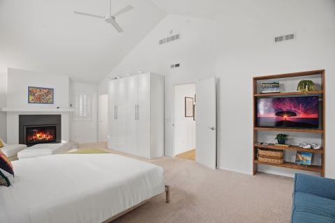 Spacious bedroom with vaulted ceilings, cozy fireplace, and entertainment center.