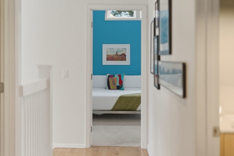A hallway leading to a bright bedroom with turquoise walls and a white sofa.