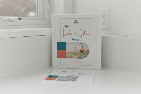 A binder for 'The Lake of the Isles Retreat' and an information card on a kitchen countertop.