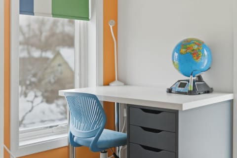 A bright study area with a globe, blue chair, and colorful walls.