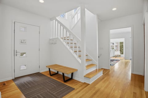 Modern entryway with hardwood floors and a staircase.