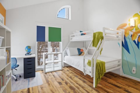 Children's bedroom featuring a white bunk bed, colorful decor, and a study area with a globe.