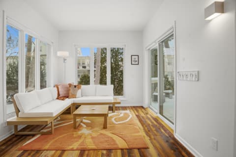 Bright living area featuring a white sofa, wooden coffee table, and large windows with a view.