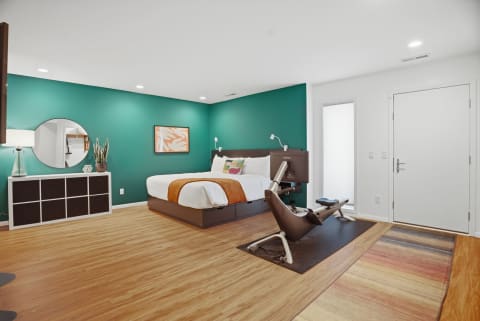 Stylish bedroom with teal wall, modern bed, and exercise equipment.
