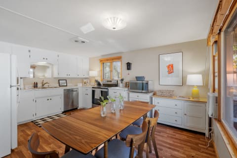 Contemporary kitchen featuring white cabinets, wooden table, and natural light.