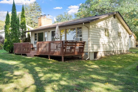 Cozy single-story house with wooden deck and green lawn.